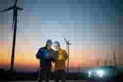 two engineers standing in windfarm at night in front of car