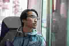 A man looking out the window while on a journey with an unmanned public transportation bus.