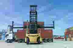 Haifa, Israel - May 11, 2020: Hyster container handler lifting a Red Shipping container off a truck and stack it on a storage platform, Wide angle image.