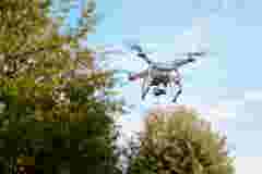 Quadcopter drone with camera flying among the trees