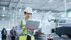 Portrait of a Happy Asian Female Engineer in Hard Hat Standing and Using Laptop Computer at Electronic Manufacturing Factory. Technician Working on Research and Development Production Plan.