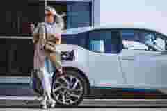 Woman on the phone charging electric car dat