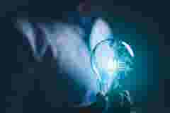 hand holding a light bulb. artificial intelligence or AI of future innovation technology concept, applying technology to business in the digital age. empowering global business AI.