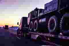 Flatbed semi truck convoy hauling armored military vehicles
