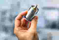 A human hand holding a small electric motor gently between thumb and index finger, shown from the side. The camera is at eye level with the subject, displaying the hand and motor in profile. The background is soft and blurred, focusing attention on the lifelike details of the motor and the skin texture. The motor reveals fine copper coils, metallic parts, and precise mechanical features. Side lighting casts realistic shadows and highlights surface textures. Ultra-detailed, photorealistic style.