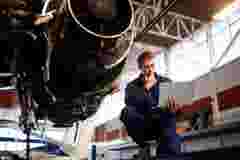 aerospace engineer doing maintenance on jet engine sitting with a labtop