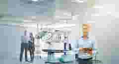medical Robotics engineer stadning infront of medical robot with team discussing data