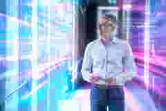 Engineer using tablet in futuristic server room with digital data