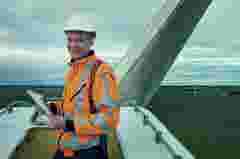 Nothing beats this view. Portrait of a young engineer inspecting a wind turbine.