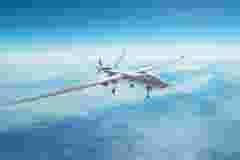 Unmanned spy military drone flies over mountains at day time.