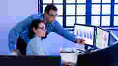 Two colleagues discussing over computer screen