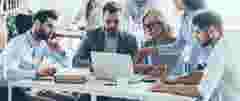 People sit around a laptop and look at content