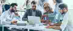 Full concentration at work. Group of young business people working and communicating while sitting at the office desk together with colleagues sitting in the background