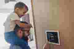 Personal audio Father holding his child and using digital thermostat