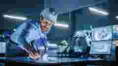 Engineer wearing hardhat uses Pen on Touchscreen of a digital table in industry meeting room