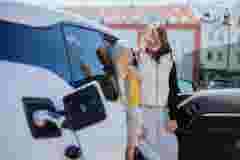 Women and teenage girl laughing merrily chatting while their electric car is charging