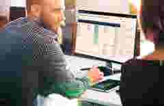 Two engineers working on desktop computer showing ReliaSoft  Cloud
