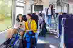 Two female friends travelling by train using mobile phone
