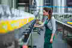 Female factory worker inspecting production line at drinks production factory