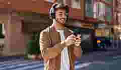 Young hispanic man smiling confident listening to music at street