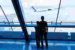 Father and son looking through the window at plane taking off at the airport